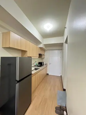 a kitchen with a stainless steel refrigerator and wooden cabinets at West Bricks in Manila