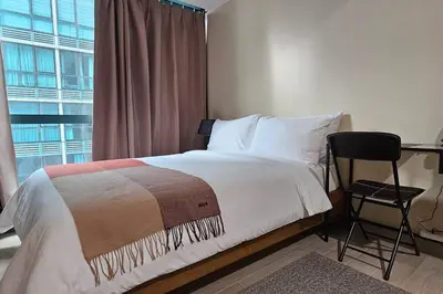 a bedroom with a bed and a desk and a window at City Life Suite Uptown BGC in Manila