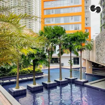 a pool with palm trees in the middle of a building at Sunshine 100 Stylish Condo by The Capital Cabin in Manila