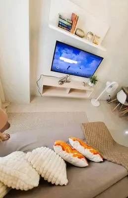 a living room with a television and pillows on a couch at Comfy Condo Near NAIA Airport in Manila