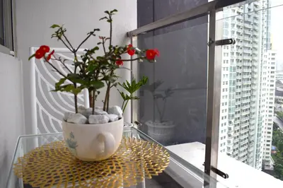 a glass table with a vase with red flowers on it at Luxe Suite at BCCT - BGC's Prime Studio - Gym, Infinity Pool with breathtaking skyline view in Manila