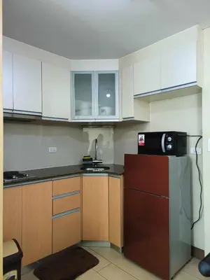 a kitchen with white cabinets and a black microwave at Two Palmtree Villas cluster3 rooms across NAIA terminal 3 in Manila