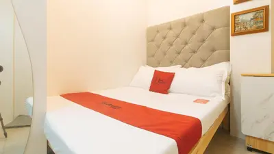 a small room with a bed with red and white pillows at RedDoorz at Delorian Residences in Manila