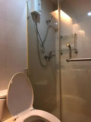 a bathroom with a toilet and a glass shower at 1-Bedroom condo with pool across NAIA Terminal 3 in Manila