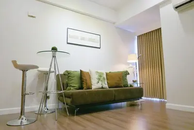 a living room with a green couch and a table at Modern 1BD in Ortigas, WiFi ,Netflix ,Pool ,Gym in Manila