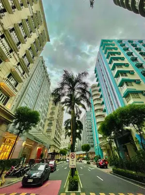 a city street with a palm tree and buildings at 101 Newport Blvd - SkyStag Aerie near NAIA T3 in Manila