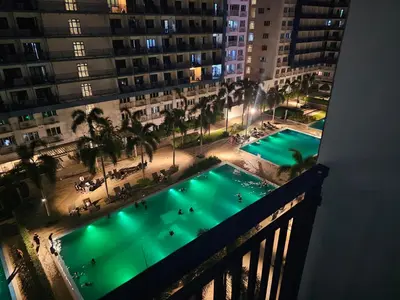 a view of a pool from a balcony at night at Moa Staycation at Sea Residences Mingchie place in Manila