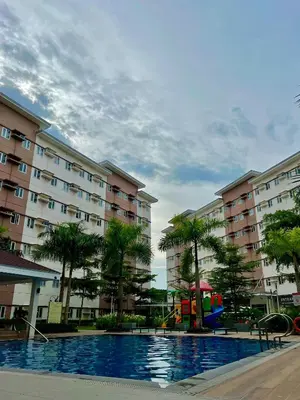 a pool with a playground in front of some buildings at Glade Suite in Trece Martires