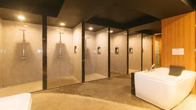 a bathroom with four shower stalls and a sink at RedDoorz Premium at JjimJBang Hotel Spa in Manila