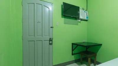 a green room with a white door and a tv at RedDoorz at Joels Apartelle in Calaboso