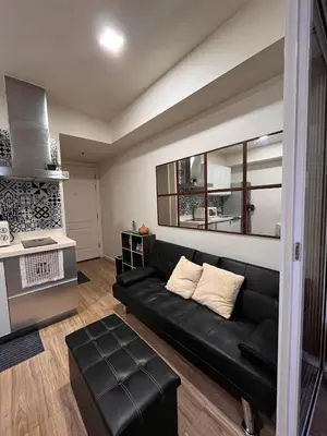 a living room with a black couch and a stove at AZURE Urban Resort Residences Paranaque City in Manila