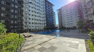 a swimming pool in the middle of two tall buildings at Urban Oasis 2BR Condo with Multiple Pools at SMDC Charm Residences in Manila