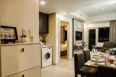 a kitchen and a living room with a table and a washer at Le Martell 1BR BGC Condo Unit - Infinity Pool & Gym Access with 360 City View in Manila