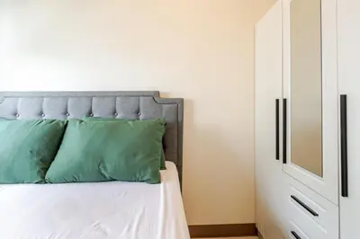 a bedroom with a bed with green pillows and a cabinet at The Prestige Bayview with Balcony in Manila