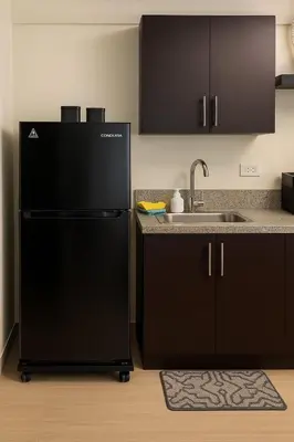 a kitchen with a black refrigerator and a sink at Kasara Urban Resort & Residences in Manila