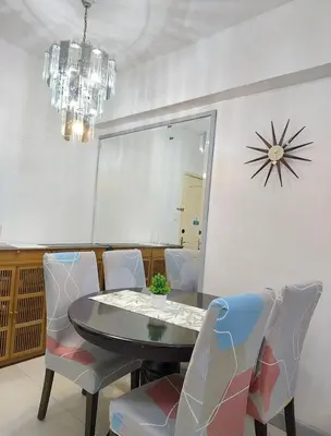 a dining room with a table and chairs and a clock at 1BR Condotel - Forbes Town Road near St Lukes BGC Taguig in Manila