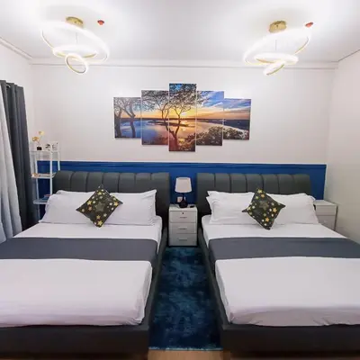 two beds in a room with two paintings on the wall at Anne's Place at Hope Residences - SMDC Condo Beside SM Trece in Trece Martires