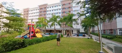 a man standing in a park in front of a building at Anne's Place at Hope Residences - SMDC Condo Beside SM Trece in Trece Martires