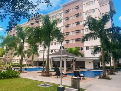 a hotel with palm trees in front of a building at Anne's Place at Hope Residences - SMDC Condo Beside SM Trece in Trece Martires