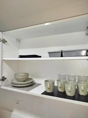 a kitchen shelf with bowls and plates on it at Air Residences-The House of Five 2Queen Bed in Manila