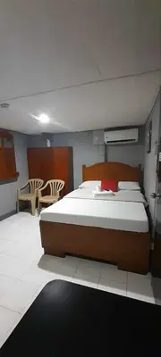 a bedroom with a large bed and a table and chairs at Slouch Hat Hotel and Restaurant in Manila