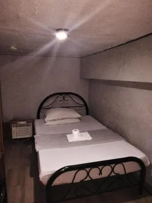 a small bed in a small room with a light at Slouch Hat Hotel and Restaurant in Manila