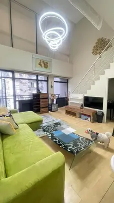 a living room with a green couch and a staircase at The Gramercy Residences Unit for Rent in Manila