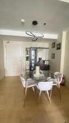 a dining room with a glass table and white chairs at The Gramercy Residences Unit for Rent in Manila