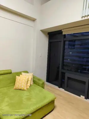 a living room with a green couch and a television at The Gramercy Residences Unit for Rent in Manila