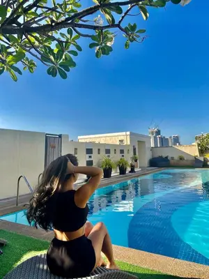a woman sitting next to a swimming pool at Elevated Staycation BGC Venice Grand Canal in Manila