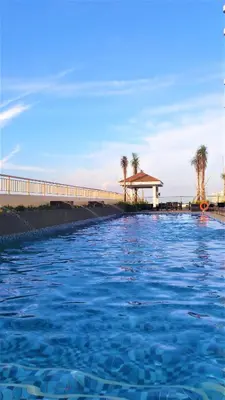 a pool of water with a gazebo and palm trees at Condo in Pasay near MOA PICC World Trade Center in Manila