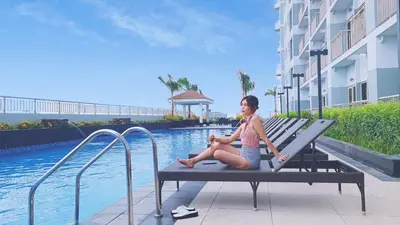 a woman sitting on a bench next to a swimming pool at Condo in Pasay near MOA PICC World Trade Center in Manila