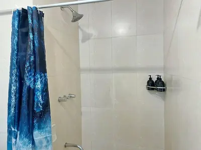 a shower with a blue shower curtain in a bathroom at Marina- Avant BGC parking w fee in Manila