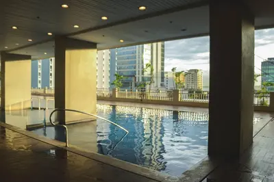 a swimming pool in a building with a view of a city at Stylish 1BR Near US Embassy & Luneta with Pool & Gym in Manila