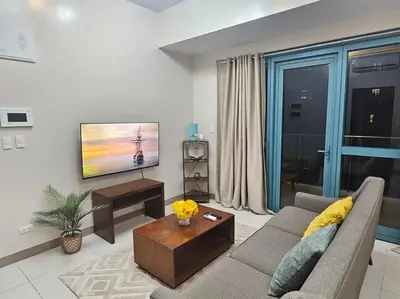 a living room with a couch and a tv at One Uptown Executive 2 bedroom, with balcony, washer & Netflix in Manila