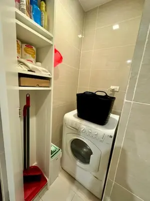 a small kitchen with a washing machine with a black basket on it at BGC 1BR unit linked to Uptown Mall with own parking in Manila