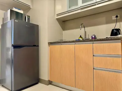 a kitchen with a stainless steel refrigerator and wooden cabinets at BGC 1BR unit linked to Uptown Mall with own parking in Manila