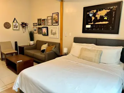 a bedroom with a large white bed and a couch at BGC 1BR unit linked to Uptown Mall with own parking in Manila