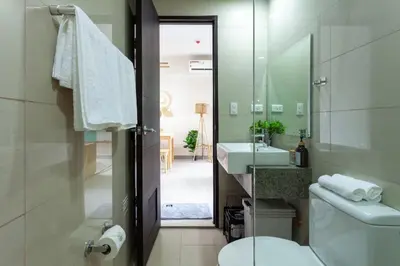 a bathroom with a toilet and a sink and a mirror at Urban Oasis Serenity in the City w Pool Gym More in Manila
