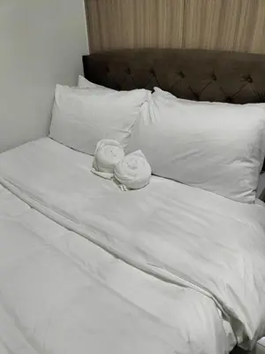 two towels on a bed with white sheets and pillows at Comfy 19 shore2 Residence Free parking, Near Airport, IKEA, MOA, Pasay City in Manila