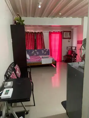 a living room with a bed and pink curtains at Hungary109 Service Apartments Near Airport at Kassel Residences in Manila