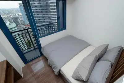 a bed in a room with large windows at Modern Living 1 Makati in Manila
