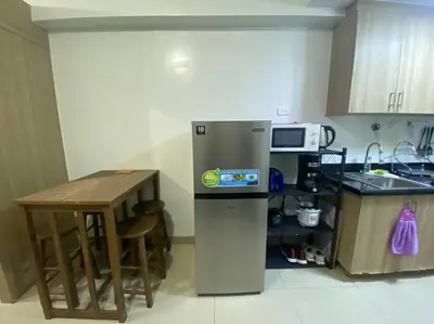 a kitchen with a refrigerator and a small table at Shore2 Condo 1BR Balcony, Wifi, Pool, MOA, Airport in Manila
