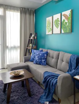a living room with a couch and a blue wall at BGC McKinley Taguig 1BR with Balcony near Venice Grand Canal mall in Manila