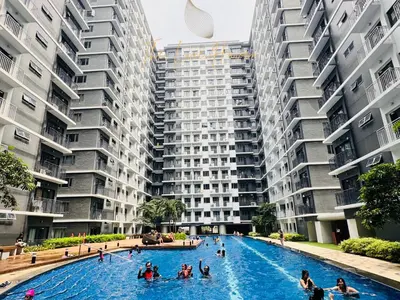 a group of people in a swimming pool in front of apartment buildings at The Luxe Haven Shore 3 Residences in Manila