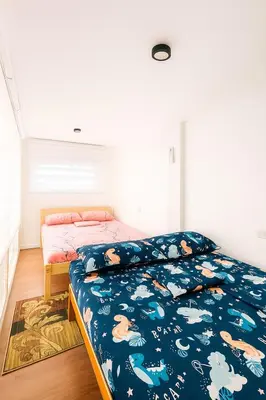 a bedroom with a bed with a blue comforter at Tinyhaven Transient Cabuyao in Cabuyao