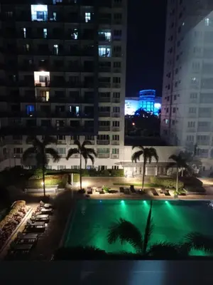 a view of a pool at night with buildings at Sea Residences Staycation Near Moa Pasay by Jhay in Manila