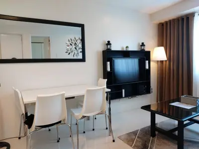 a room with a table and chairs and a television at Condo Studio Luxe in Princeton Residences in Manila