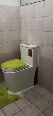 a toilet with a green lid in a bathroom at USO House in Manggahan