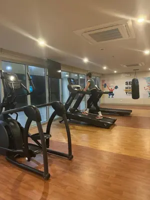 a woman running on a treadmill in a gym at Stylish 1BR Near Airport Facing the Bay - 7b in Manila
